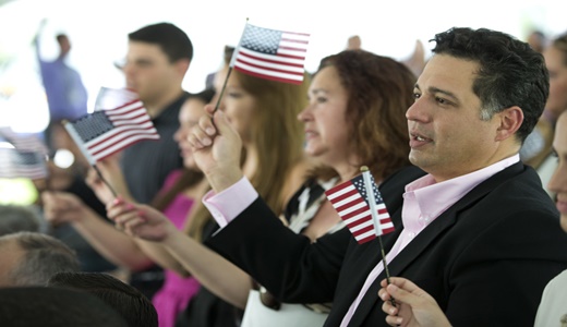 New citizens wave American flags during a U.S. Citizenship and Immigration Services naturalization ceremony on the campus of Florida International University, Monday, July 6, 2015, in Miami. (AP Photo/Wilfredo Lee)